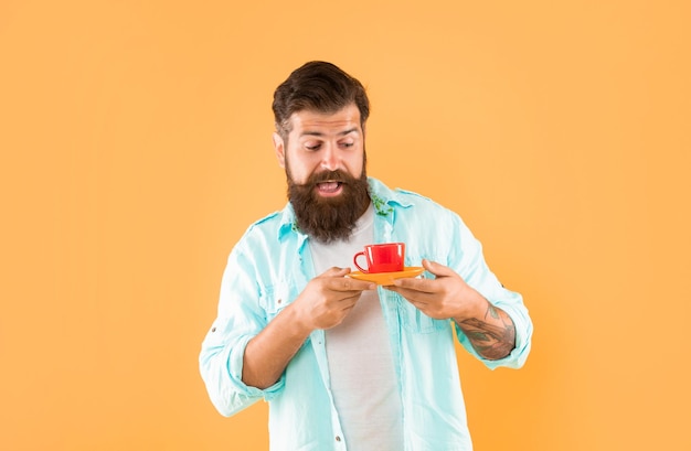 amazed mature hipster with beard holding coffee cup on yellow background coffee