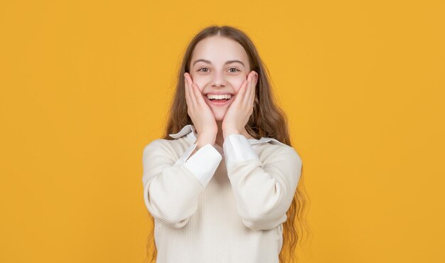 Amazed positive teen girl on yellow background