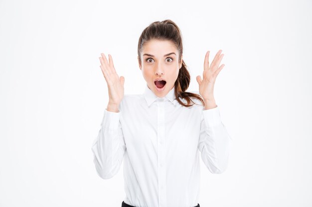 Amazed pretty young businesswoman with raised hands