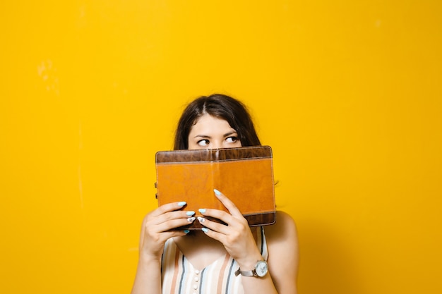 Amazed pretty young woman covered her face with book