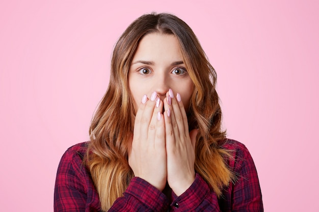 Amazed scared young pretty female dressed in checkered shirt