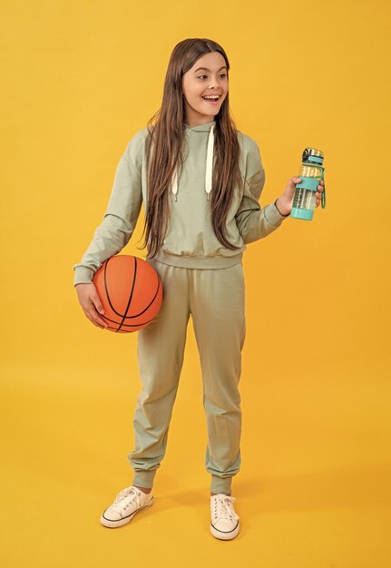 Photo amazed teen basketball girl isolated on yellow teen basketball girl in studio