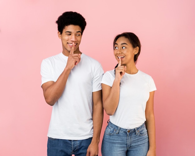 Amazed teen couple make silence sign keep forefingers on lips