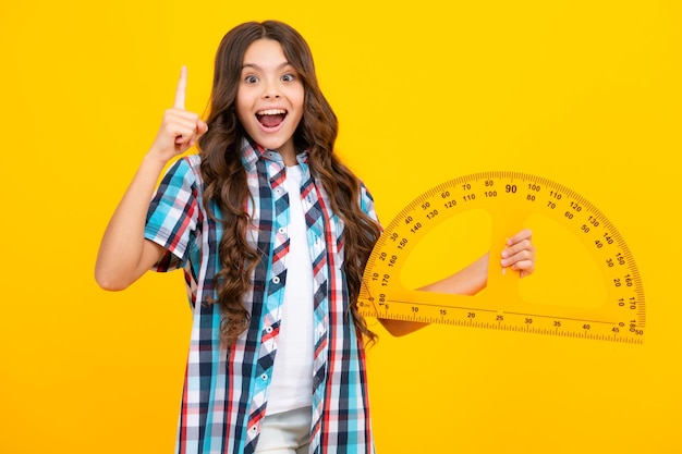 Amazed teen girl Back to school School girl hold ruler measuring isolated on yellow background