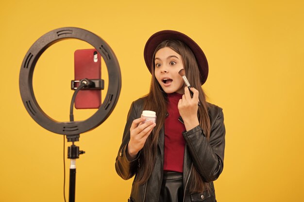 Amazed teen girl blogger use selfie led lamp and smartphone selfie