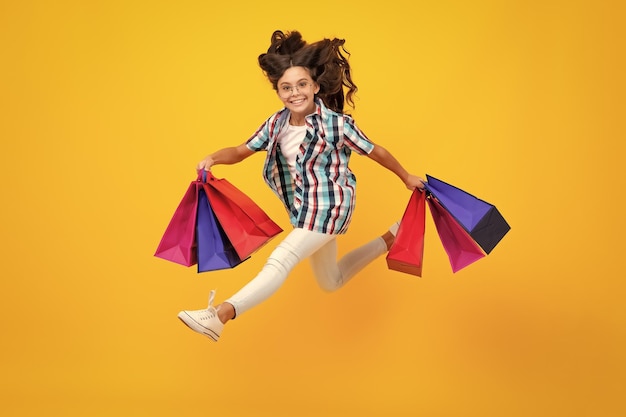 Amazed teen girl girl teenager with shopping bags isolated on yellow backgound shopping and sale concept excited expression cheerful and glad