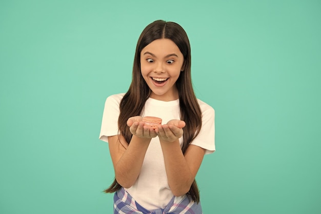 Amazed teen girl hold french macaron or macaroon cookies confectionary