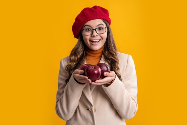 Amazed teen girl with apple isolated on yellow background teen girl hold apple