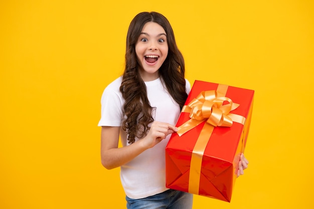 Amazed teenager Child teen girl 1214 years old with gift on yellow isolated background Birthday holiday present concept Excited teen girl