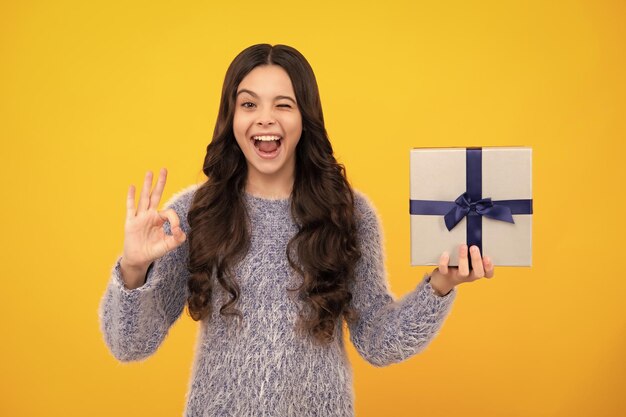 Amazed teenager child with gift present box on isolated studio background gifting for kids birthday excited teen girl