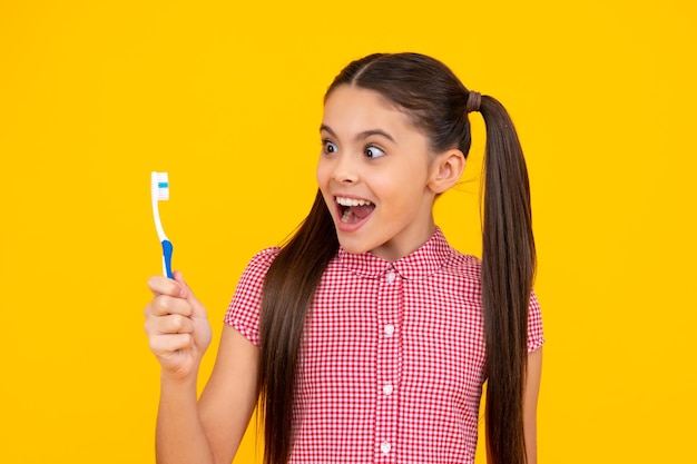 Photo amazed teenager funny teen girl brush her teeth dental healthy concept isolated over yellow