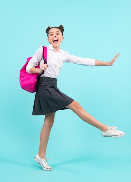 Изумленный подросток Школьница с рюкзаком Студент-подросток на синем изолированном фоне Прыжок