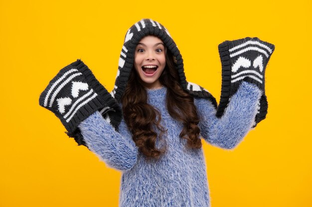 Photo amazed teenager warm hat with hood and scarf modern teen girl wearing sweater and knitted hat on isolated yellow background excited teen girl