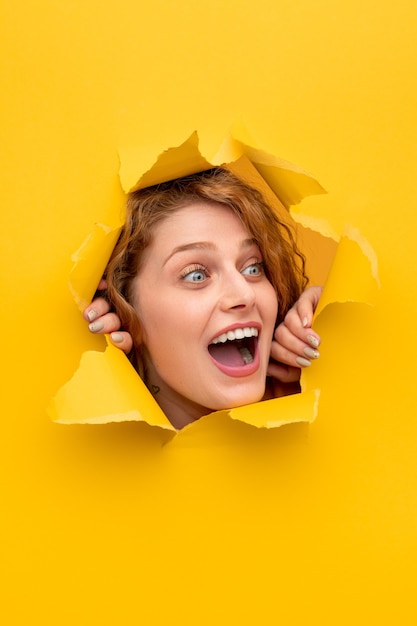 Amazed woman peeking out from hole in paper