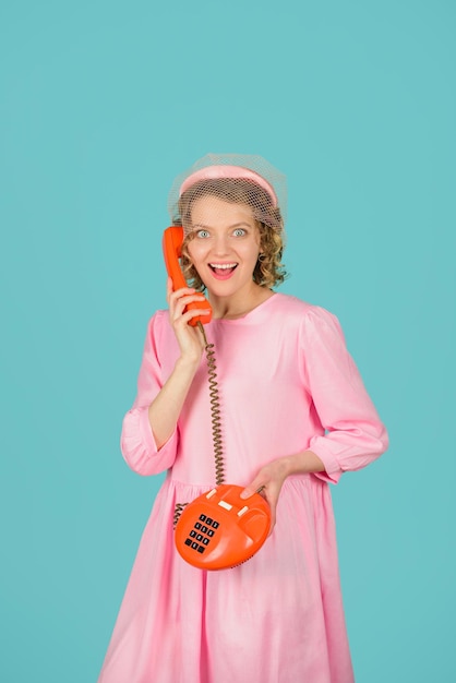 Amazed woman in pink dress with telephone handset woman talking on retro phone communication pretty