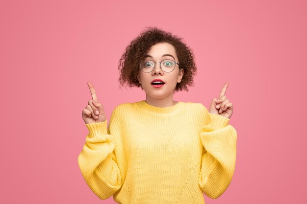 Amazed woman pointing up in studio