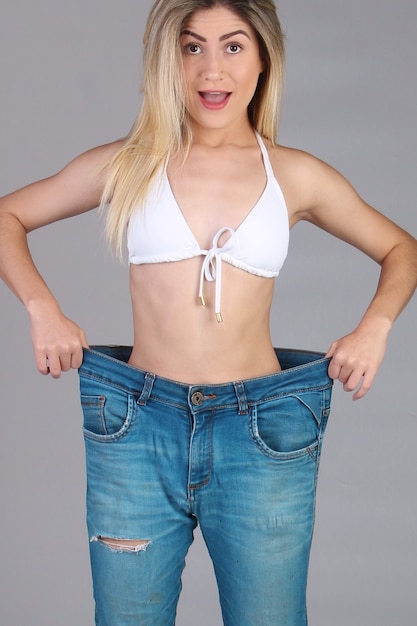 Photo amazed woman pulling baggy pants showing that she lost weight