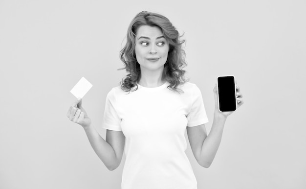 Amazed woman showing credit or debit card and smartphone to make online shopping online business