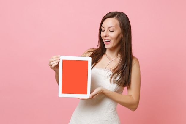 Amazed woman in white dress holding looking on digital tablet with blank black empty screen