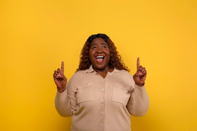 Photo amazed young african american chubby woman pointing at copy space