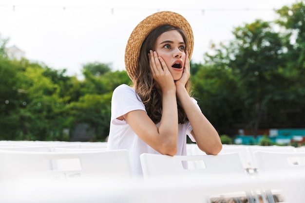 夏に屋外の都市公園に座って驚いた少女