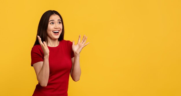 Amazed young korean woman looking at copy space and gesturing