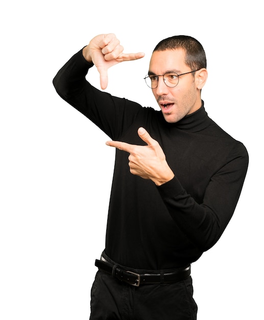 Amazed young man making a gesture of taking a photo with the hands