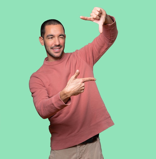 Amazed young man making a gesture of taking a photo with the hands