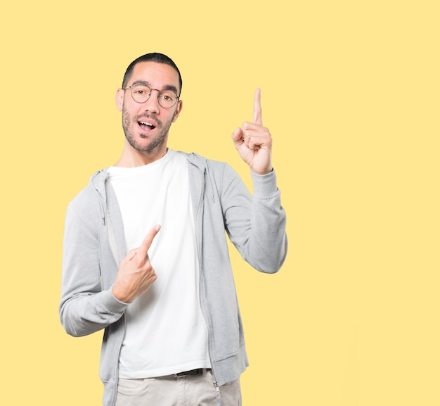 Amazed young man pointing up with his finger