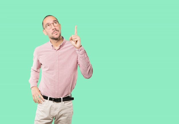 Amazed young man pointing up with his finger