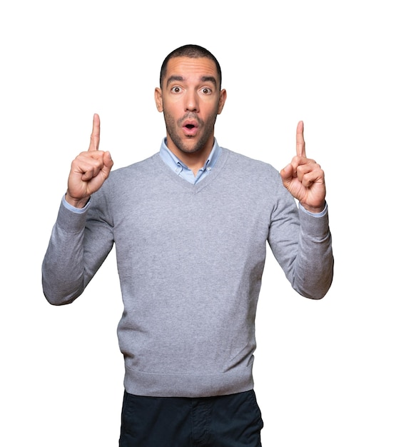 Amazed young man pointing up with his finger