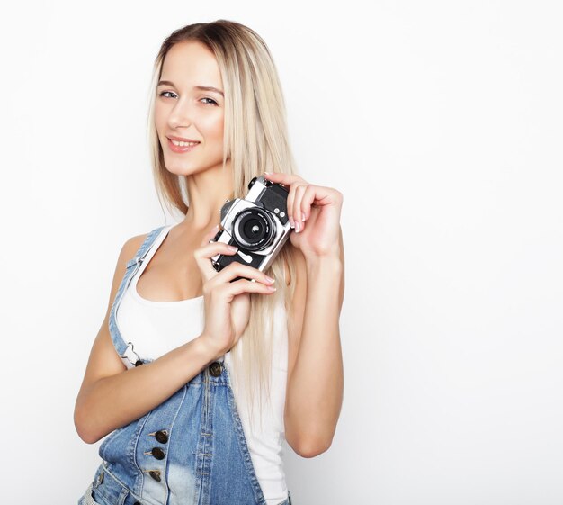 Foto giovane bella donna stupita che tiene la telecamera sullo sfondo bianco