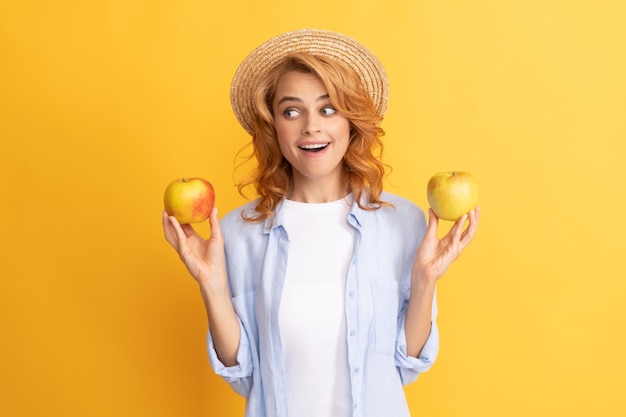 Amazed young woman curly hair in summer straw hat with apple fruit