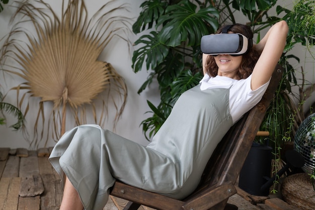 Amazed young woman using VR in home garden resting in relaxing virtual environment Cyberspace