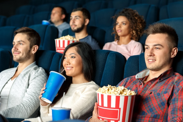 Stupore nel cinema. un colpo del primo piano di tre amici che godono guardando i film insieme al cinema