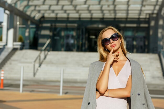 Incredibile signora bionda con gli occhiali alla moda in posa sul viale in una giornata di sole. spazio per il testo