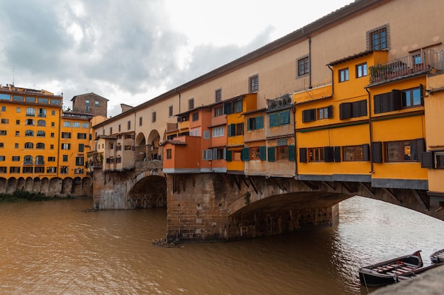 Amazing bright yellow bridge with old houses in the city of Florence Italy