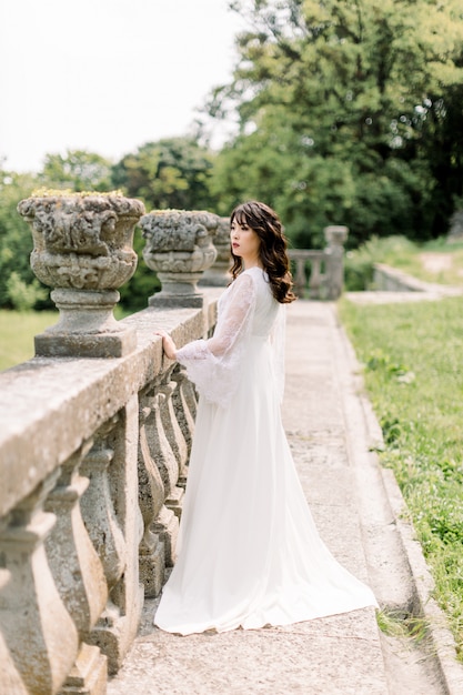 Amazing brunette Chinese Asian bride in luxury wedding dress, posing in old castle