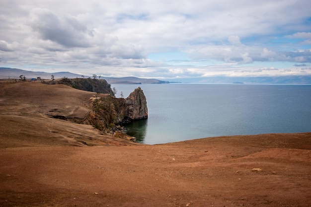 Amazing cape on the background of Lake Baikal Rocky shore The sky is cloudy The water is calm Horizontal