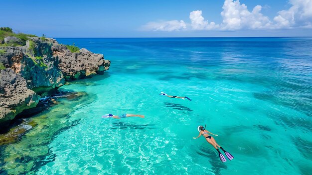 Amazing clear water of the Caribbean sea with three people snorkeling near the rocky coast