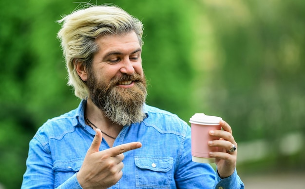 Amazing coffee enjoys relaxing on weekend morning drinks\
concept student on coffee break bearded man drinking coffee while\
walking outdoors bearded hipster guy wearing casual clothes