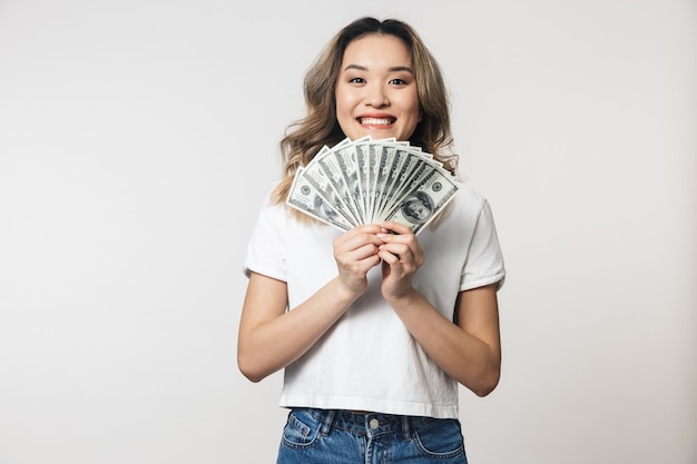 amazing cute young woman posing isolated over white wall wall holding money