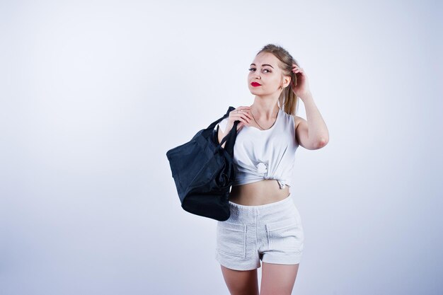 Amazing fit sexy body brunette caucasian girl posing at studio against white background on shorts and top with black sport bag