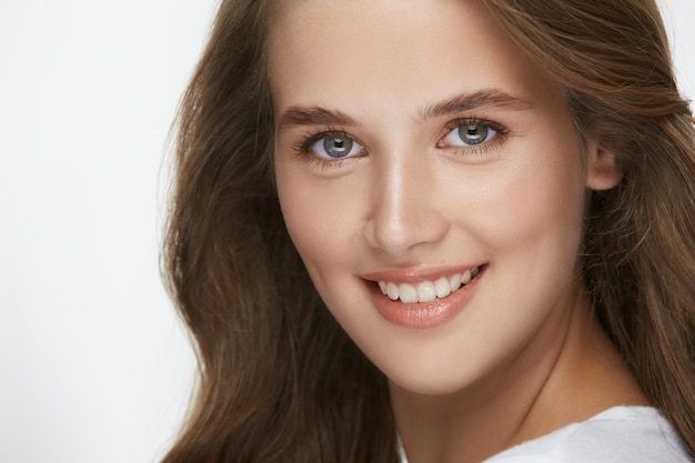 Incredibile ragazza con un perfetto sorriso bianco e capelli ricci che guarda alla fotocamera