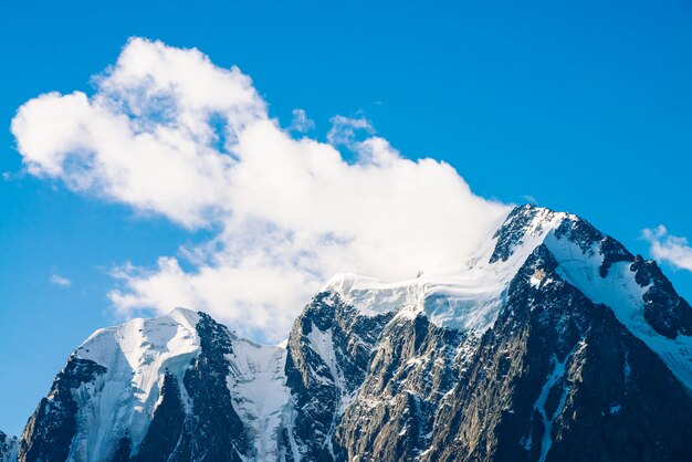 Amazing glacier under blue sky. Huge cloud on giant wonderful snowy mountains in sunlight. Atmospheric minimalist mountain landscape of majestic nature in sunny day.