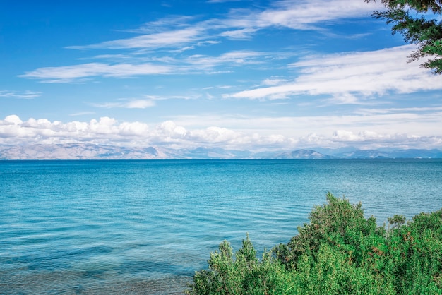 Amazing green bay with crystal clear water, big stones on Corfu island, Greece. Beautiful landscape of Ionian sealine. Sunny weather, blue sky.