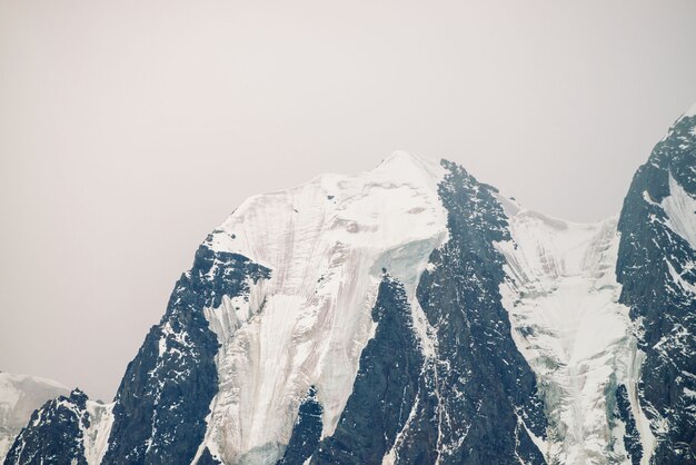 Incredibile cima del ghiacciaio enorme. catena montuosa di snowy in cielo nuvoloso. meravigliosa cresta rocciosa gigante con neve nella nebbia. atmosferico paesaggio minimalista di natura maestosa degli altopiani. tranquillo paesaggio montano.