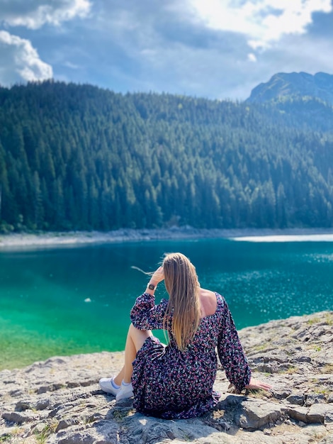 놀라운 호수와 머리를 흔들며 호수 근처에 앉아있는 금발 소녀 고독 휴식의 개념