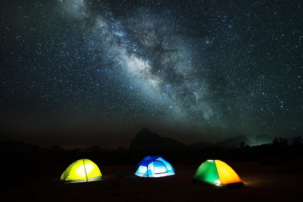 山の上の夜空に浮かぶ天の川の素晴らしい風景と、頂上の山にキャンプテントでピクニックをする冒険と屋外旅行のコンセプト