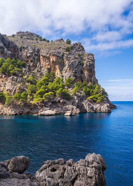 Amazing landscapes of Mallorca The mountains are covered with greenery the sea is blue and transparent Sunny day clouds over a rocky ridge Mallorca Spain Balearic Islands